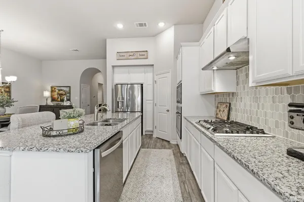 a kitchen with granite countertop stainless steel appliances a sink stove and cabinets