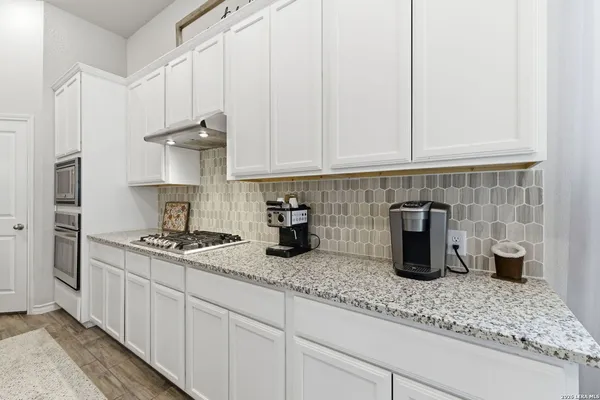 a kitchen with granite countertop white cabinets and a sink