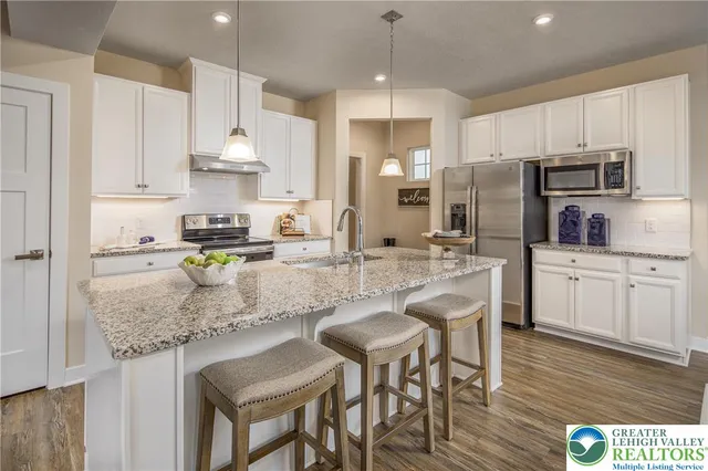 a kitchen with stainless steel appliances granite countertop a stove refrigerator a sink a stove a dining table and chairs with wooden floor