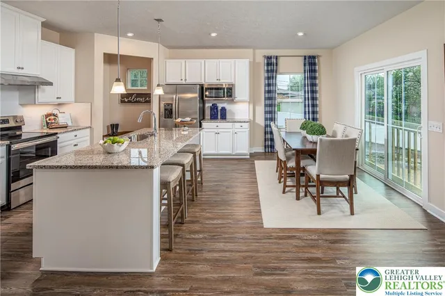 a kitchen with stainless steel appliances granite countertop a table chairs refrigerator and sink