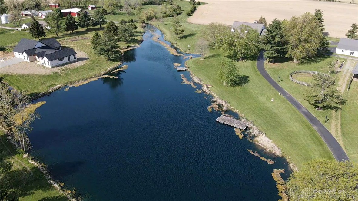 3489 Harlan-Carroll Road Waynesville, OH 45068 - Photo 96 of 98 This aerial view showcases a serene pond with docks, surrounded by lush green landscapes and residential structures.