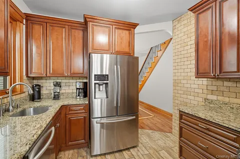a kitchen with granite countertop a refrigerator and wooden cabinets