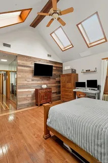 a bedroom with a bed a flat screen tv and chandelier