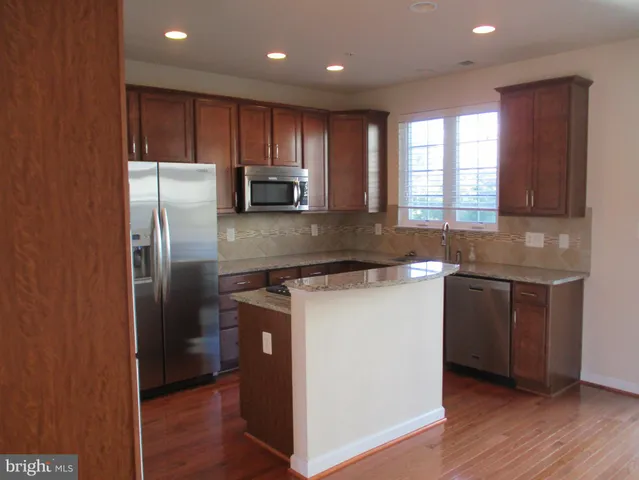 a kitchen with stainless steel appliances a sink a stove a microwave a refrigerator and cabinets