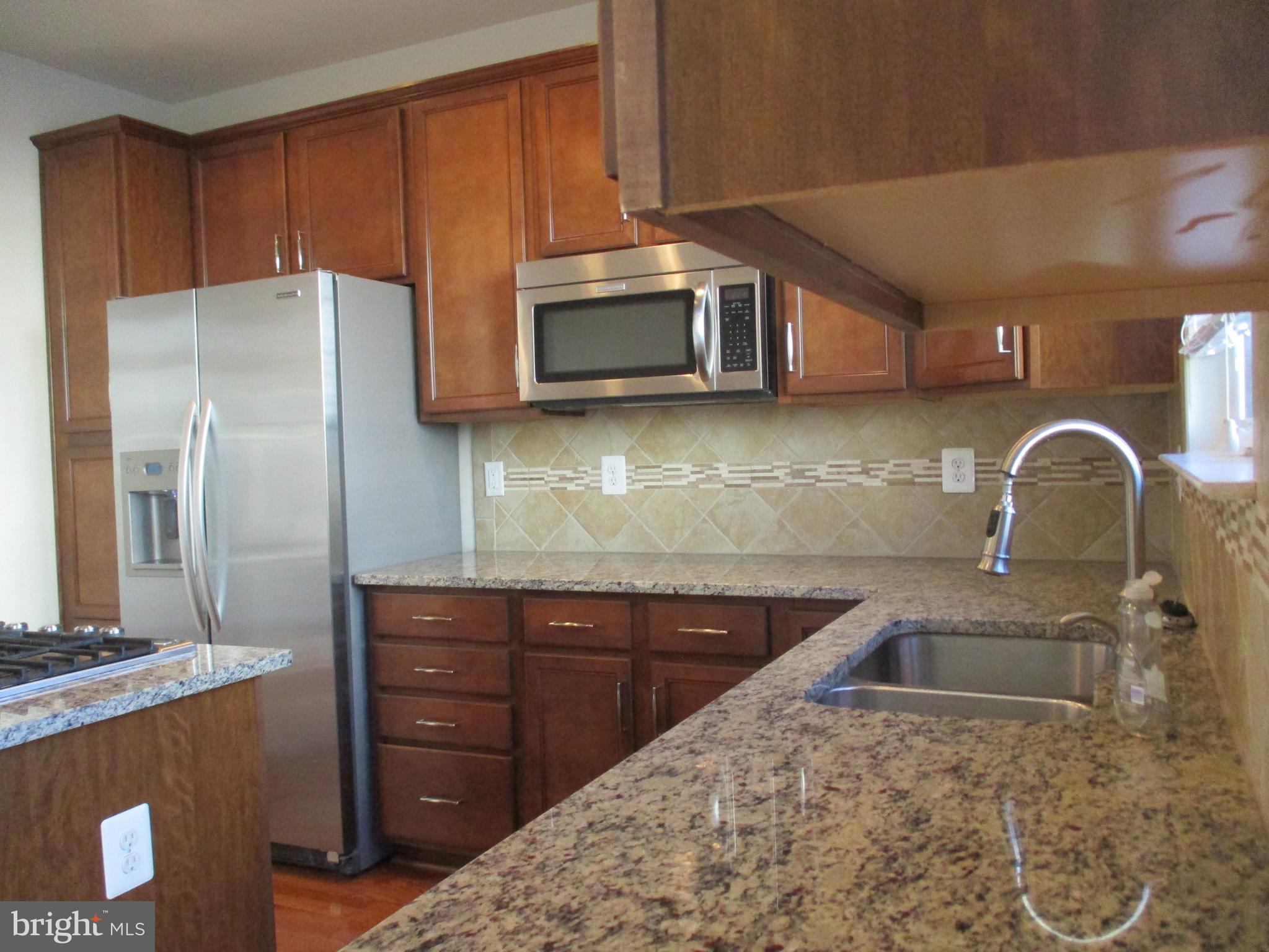 2144 Little Sorrel Way Silver Spring, MD 20902 - Photo 30 of 31 a kitchen with stainless steel appliances a sink a stove a microwave a refrigerator and cabinets