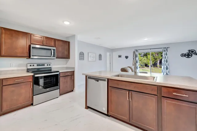a kitchen with stainless steel appliances granite countertop a stove a sink and a microwave