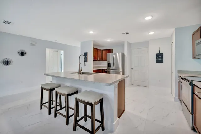 a kitchen with stainless steel appliances granite countertop a kitchen island hardwood floor and a sink