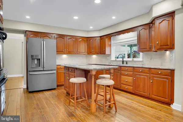 a kitchen with granite countertop wooden floors and white stainless steel appliances