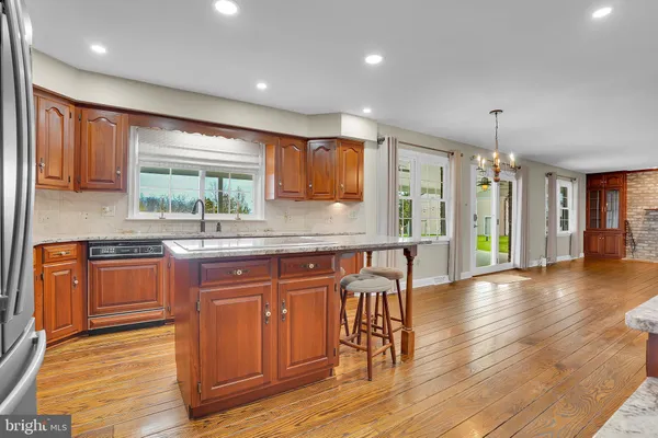 a kitchen with stainless steel appliances granite countertop wooden floors a stove a sink and a window