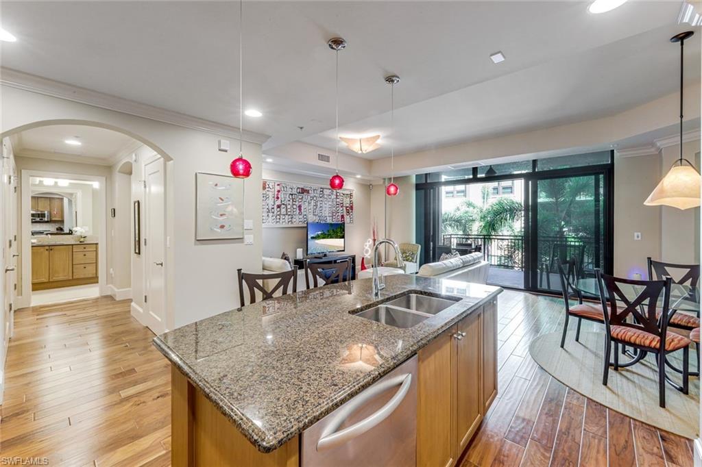 9123 Strada Place, Unit 7201 Naples, FL 34108 - Photo 7 of 50 a kitchen with stainless steel appliances granite countertop a kitchen island a stove a table and chairs with wooden floor