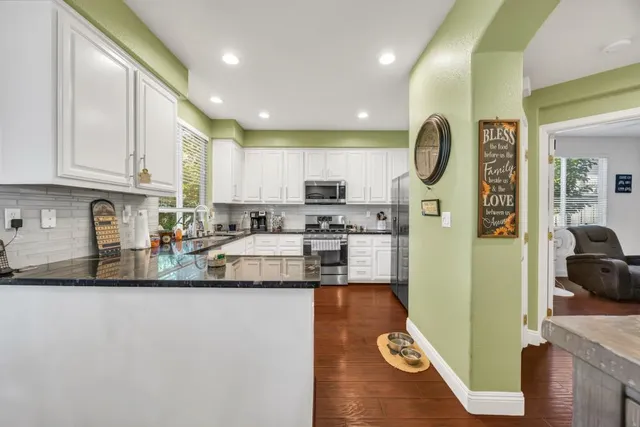 a kitchen with stainless steel appliances granite countertop a refrigerator a stove top oven a sink and cabinets