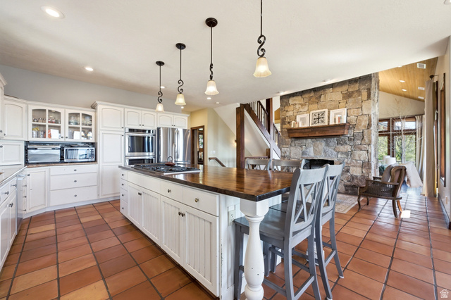 335 Bern Way Midway, UT 84049 - Photo 21 of 88 Open-concept kitchen with a large center island, white cabinetry, stainless steel appliances, and terracotta tile flooring