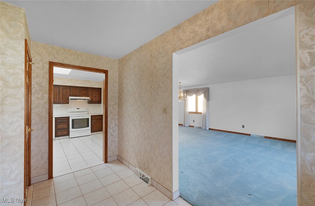 5611 Ralston Drive Parma, OH 44129 - Photo 26 of 39 Hall featuring light tile patterned floors, a chandelier, wallpapered walls, and light carpet