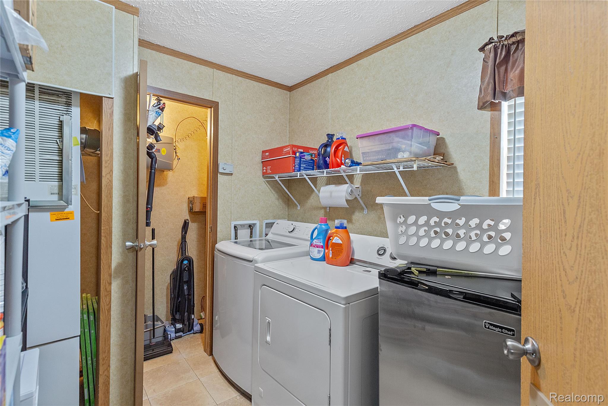 111 Riviera Oxford, MI 48371 - Photo 8 of 22 Laundry area featuring ornamental molding, a textured ceiling, light tile patterned floors, washer and dryer, and wallpapered walls