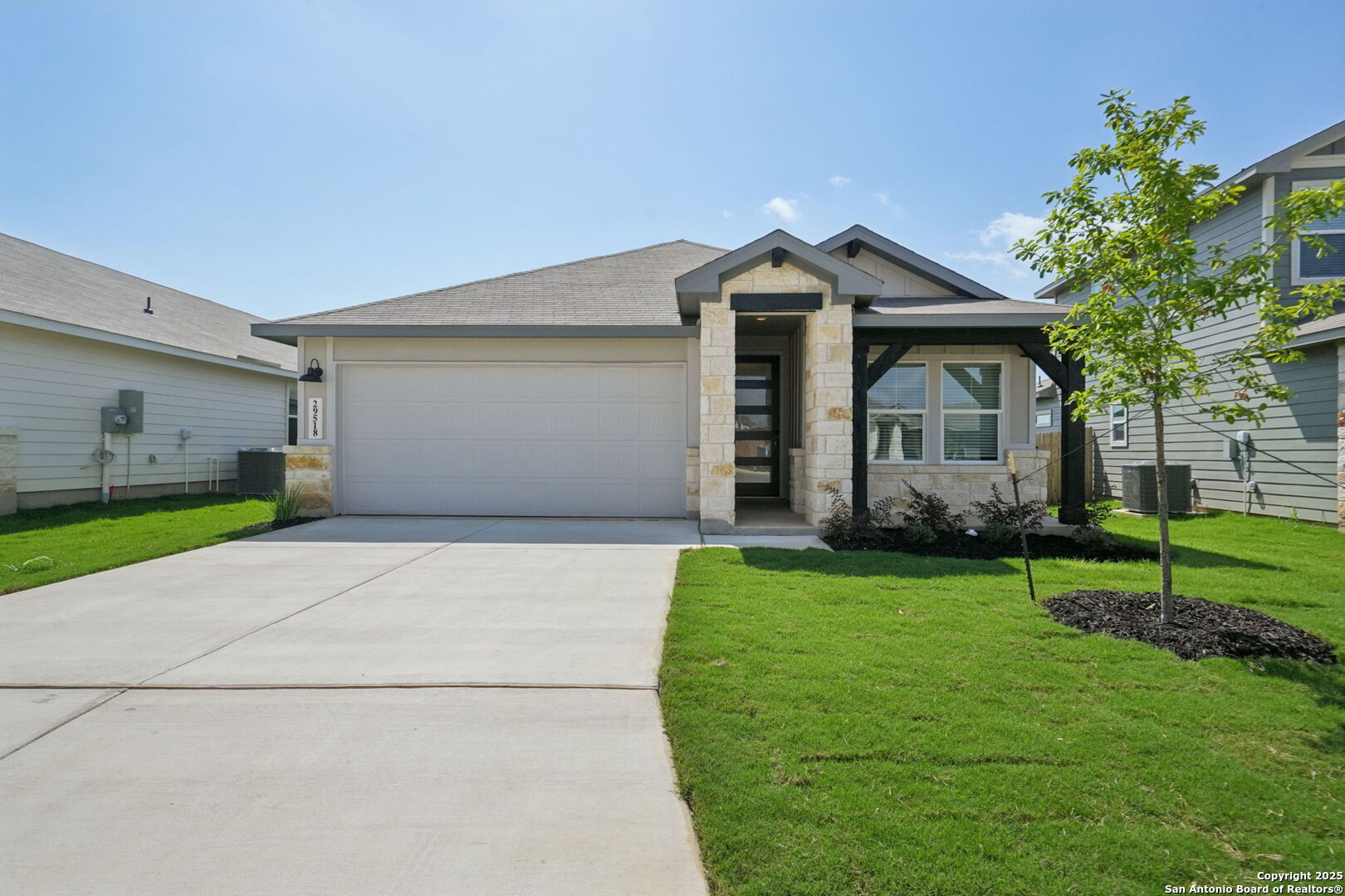 a view of a white house next to a yard and a large tree
