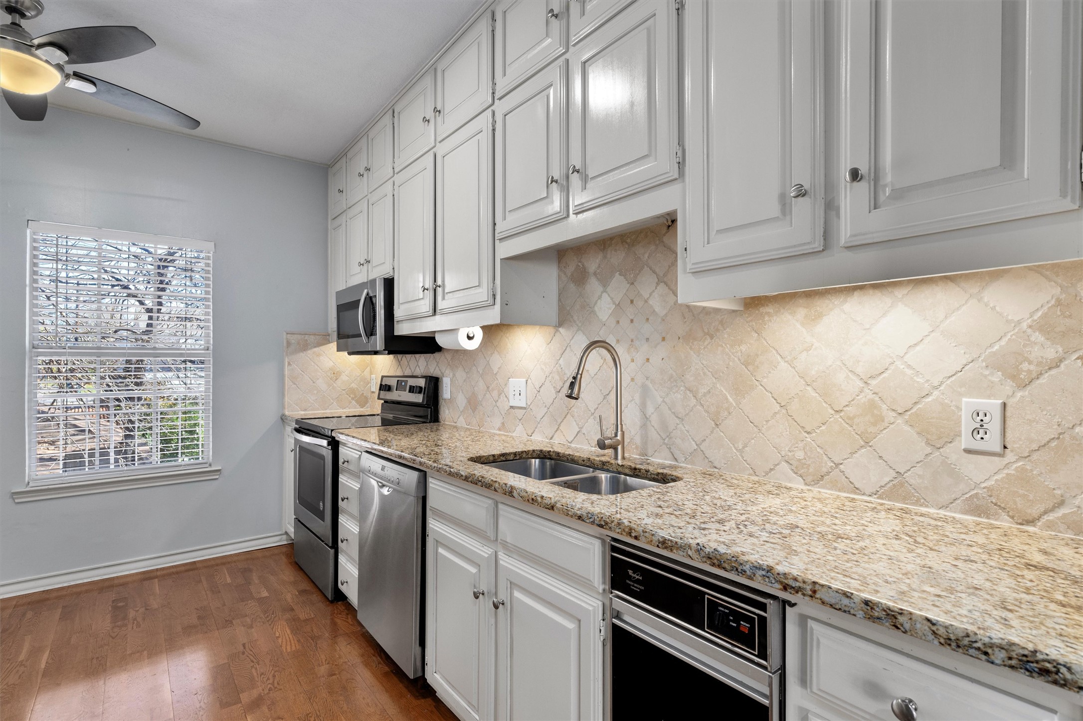 2408 Enfield Road, Unit 212 Austin, TX 78703 - Photo 1 of 1 Kitchen with stainless steel appliances, light stone counters, dark wood finished floors, white cabinets, and ceiling fan