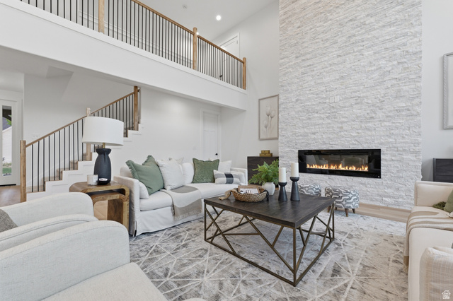 702 Alpine Highway Alpine, UT 84004 - Photo 26 of 83 Two-story living area featuring a stacked stone fireplace with a linear insert, a grand staircase with wood newel posts and black metal balusters, and a second-story overlook