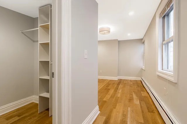 a view of an empty room with window and wooden floor