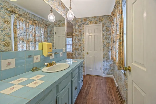 a bathroom with a granite countertop sink a toilet a mirror and shower