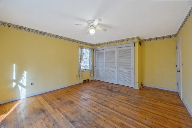 a view of an empty room with window and wooden floor