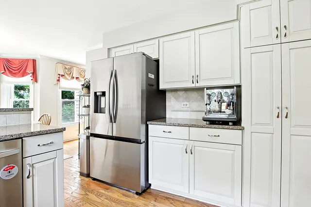 a kitchen with stainless steel appliances white cabinets and wooden floors