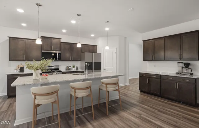 a kitchen with a dining table chairs wooden floor cabinets appliances and a window
