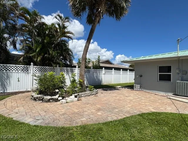 a backyard of a house with table and chairs under an umbrella