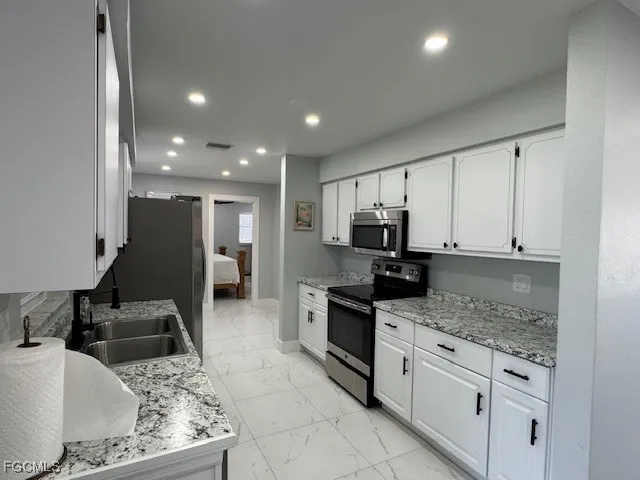 a kitchen with stainless steel appliances granite countertop a sink stove and refrigerator