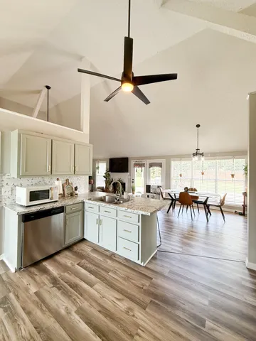 a kitchen with stainless steel appliances granite countertop a stove oven a dining table and chairs with wooden floor