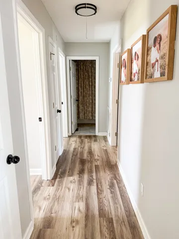 a view of a hallway with wooden floor and closet