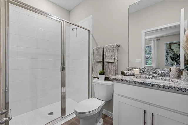 a bathroom with a granite countertop sink toilet and shower