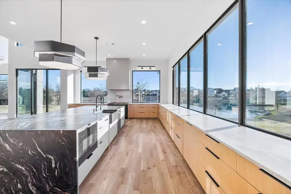 a large kitchen with kitchen island a large counter top stainless steel appliances and a large window