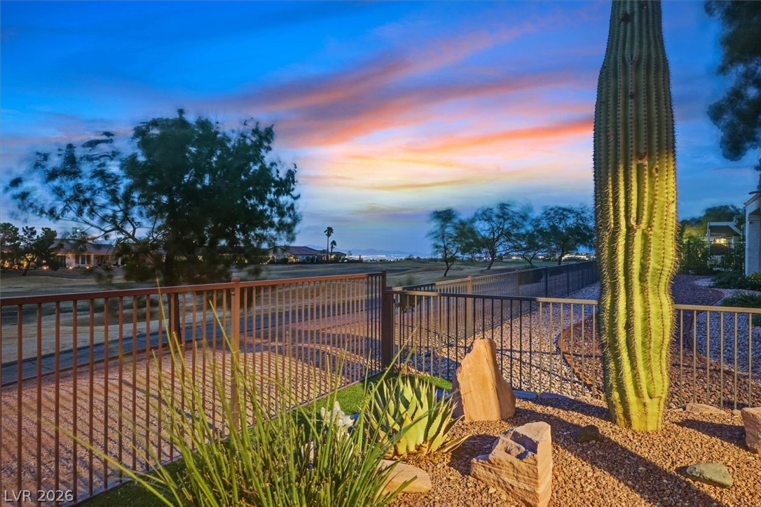 1823 Baton Rouge Street Henderson, NV 89052 - Photo 34 of 60 Desert landscaping and a secure metal fence overlook the neighboring golf course under twilight skies.