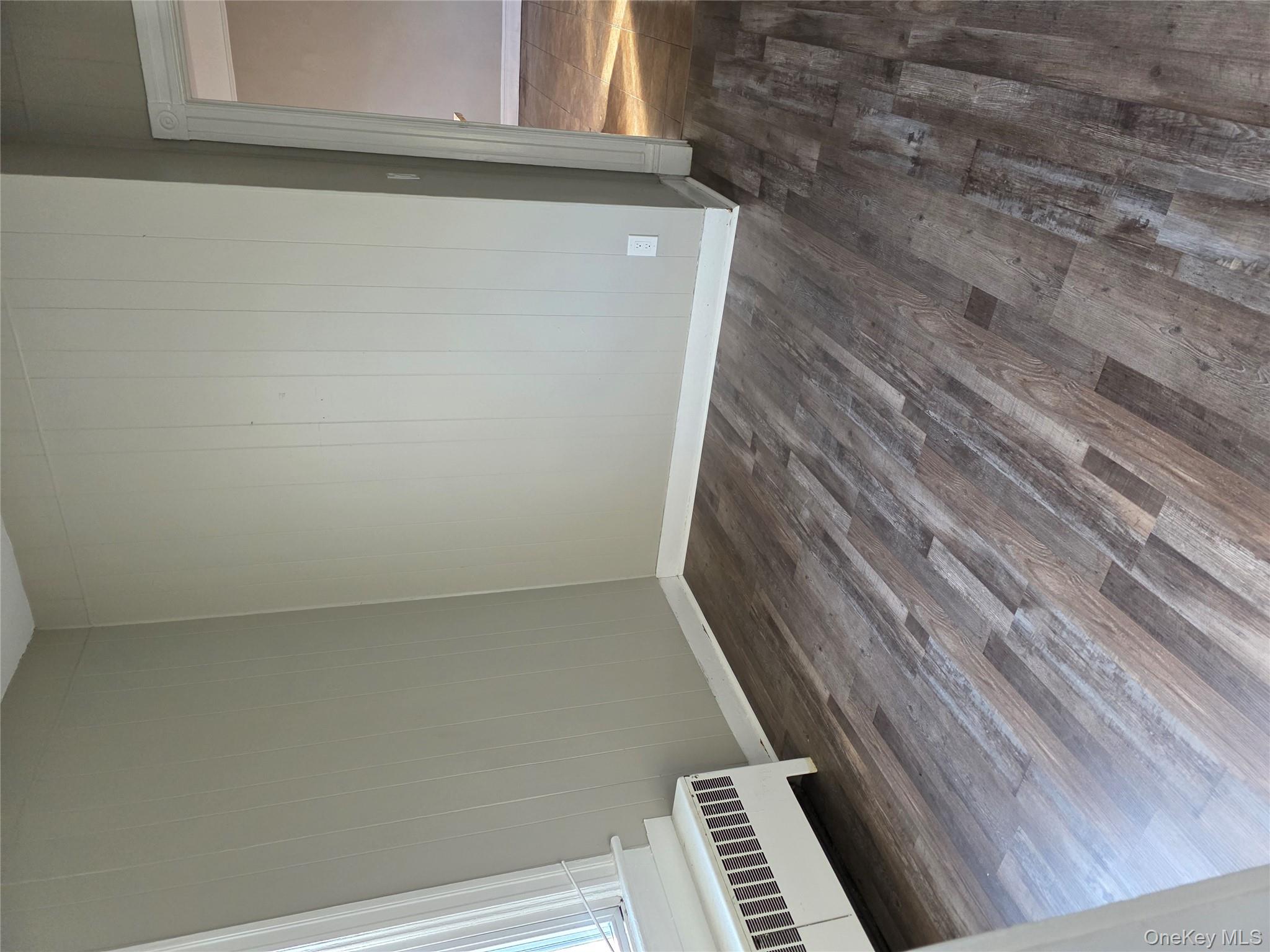 18 Davis Street Poughkeepsie, NY 12601 - Photo 2 of 14 Unfurnished room with dark wood finished floors, radiator, and wood walls