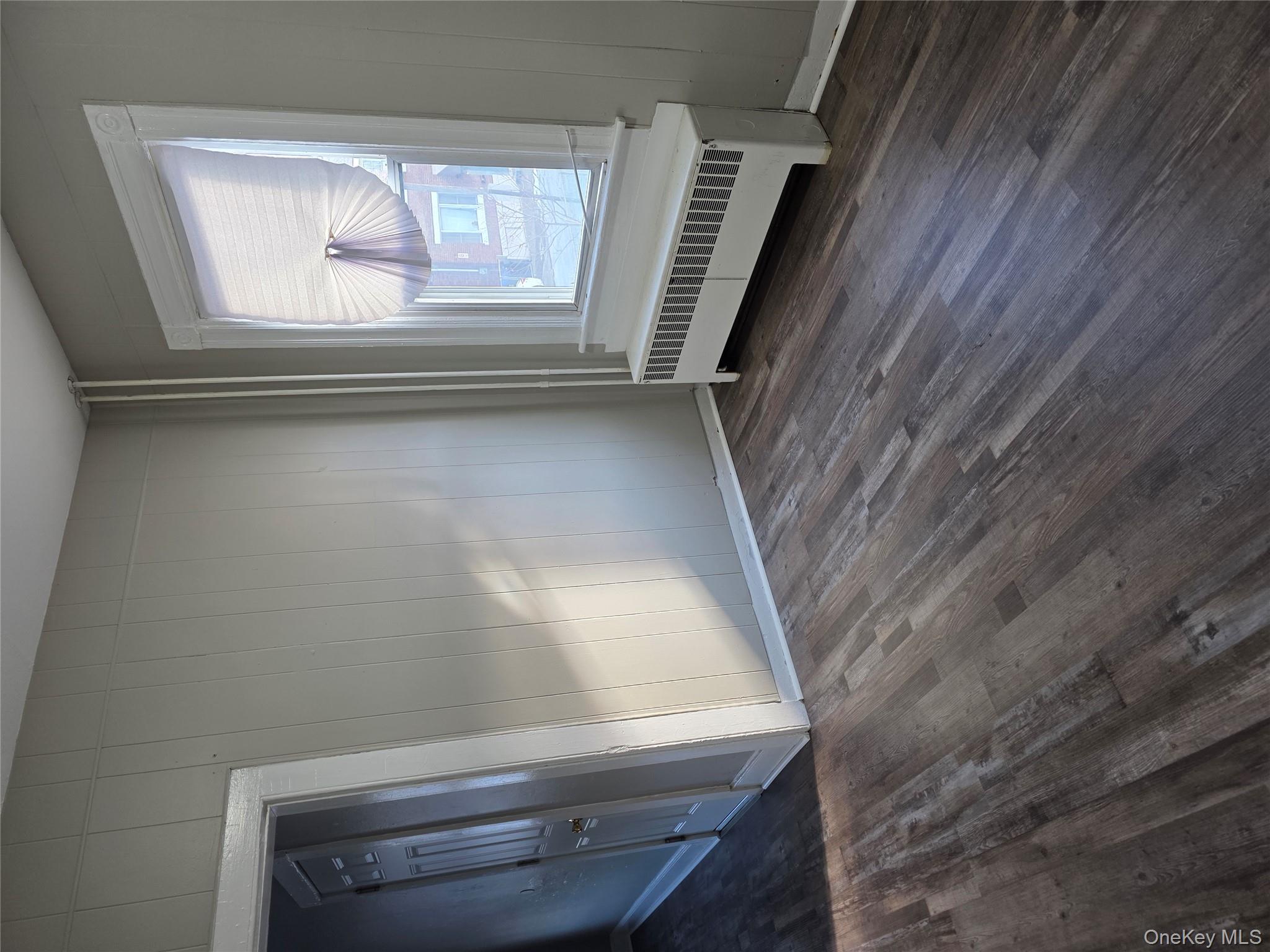 18 Davis Street Poughkeepsie, NY 12601 - Photo 4 of 14 Unfurnished room with radiator heating unit, dark wood-style flooring, and wooden walls