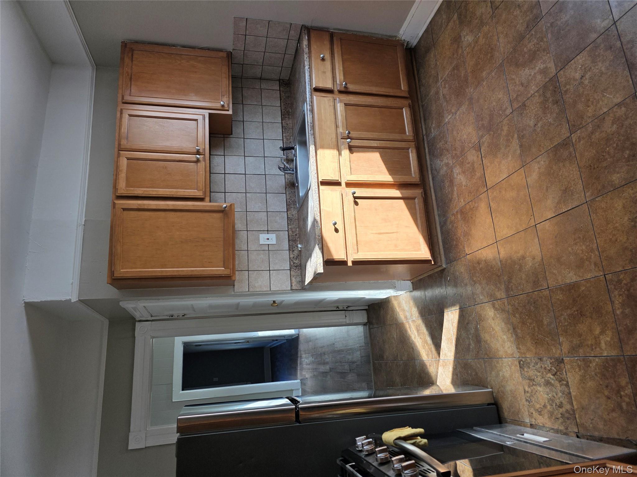 18 Davis Street Poughkeepsie, NY 12601 - Photo 5 of 14 Kitchen with stove, brown cabinetry, tasteful backsplash, dark countertops, and refrigerator