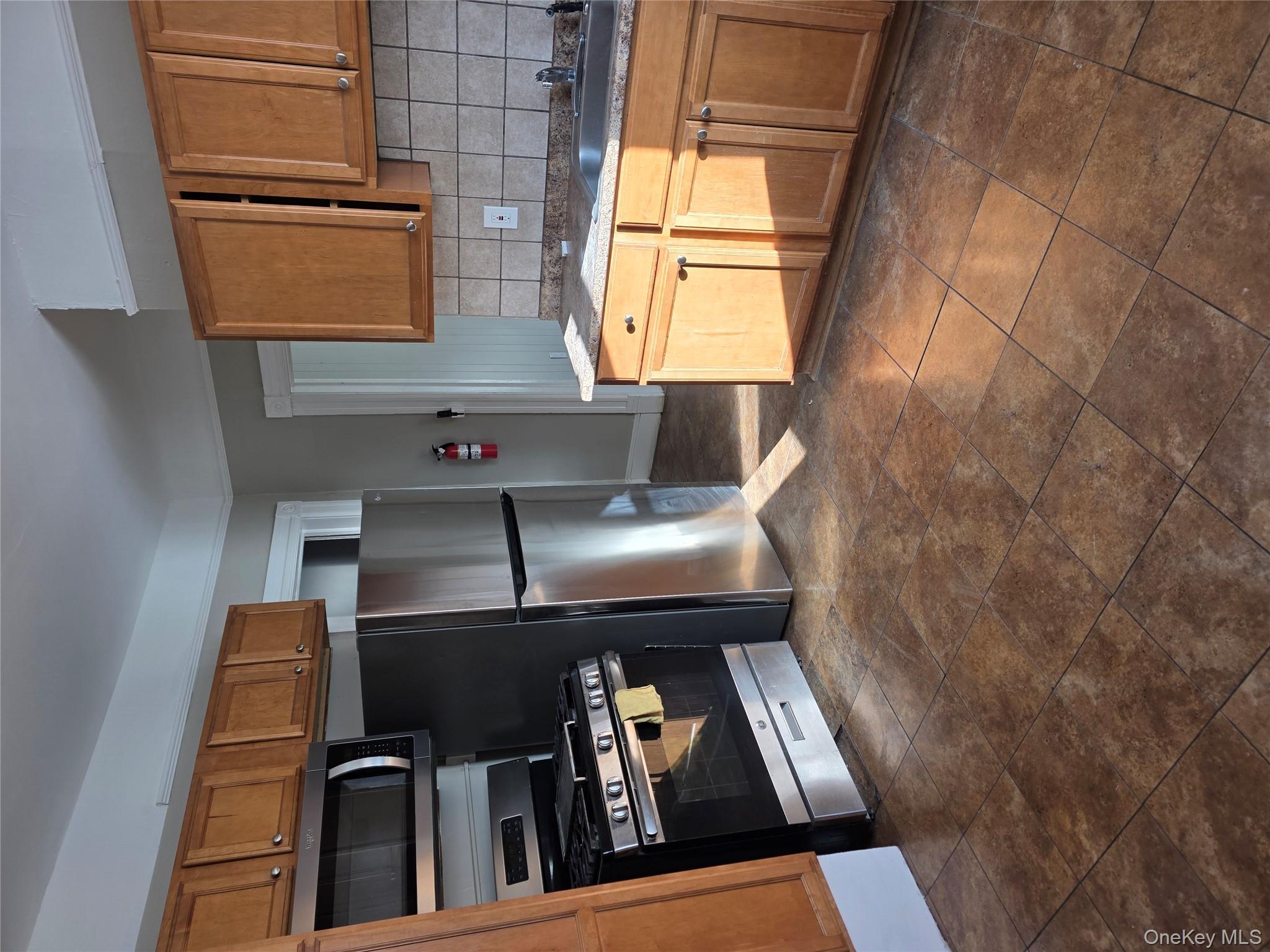 18 Davis Street Poughkeepsie, NY 12601 - Photo 6 of 14 Kitchen with brown cabinets, range, backsplash, and freestanding refrigerator