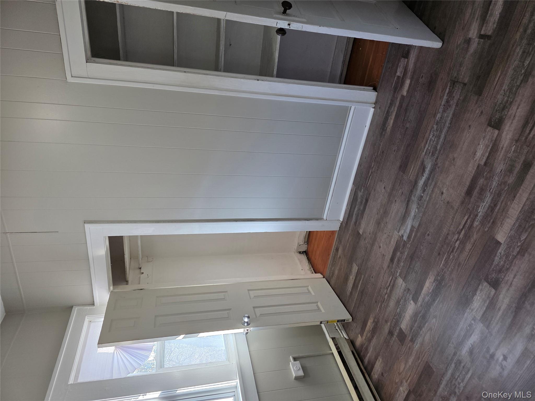 18 Davis Street Poughkeepsie, NY 12601 - Photo 7 of 14 Unfurnished bedroom featuring dark wood-style floors, wooden walls, and a baseboard radiator