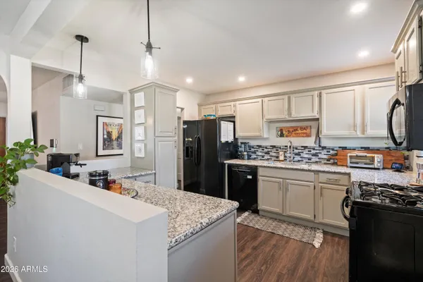a kitchen with stainless steel appliances kitchen island granite countertop a dining table chairs and view living room