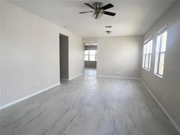 a view of an empty room with a window and wooden floor