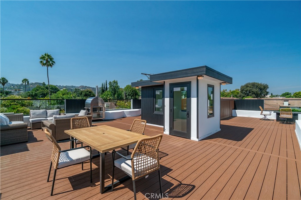 13838 Milbank Street Sherman Oaks, CA 91423 - Photo 42 of 57 a view of a patio with a table and chairs under an umbrella with wooden floor and fence