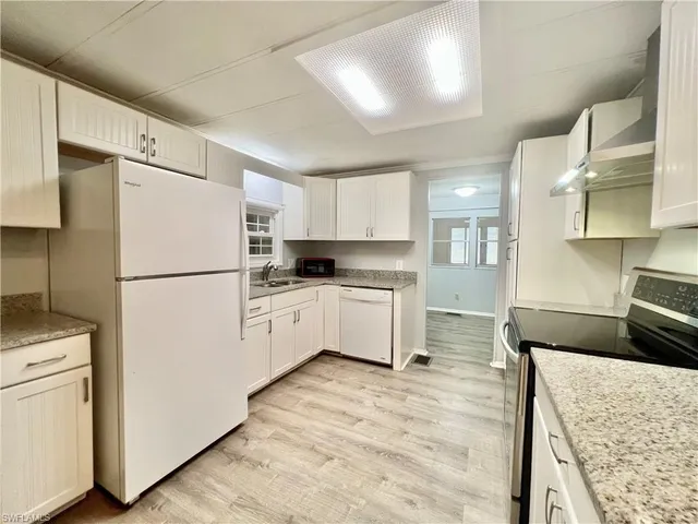 a kitchen with a refrigerator a stove top oven a sink and cabinets