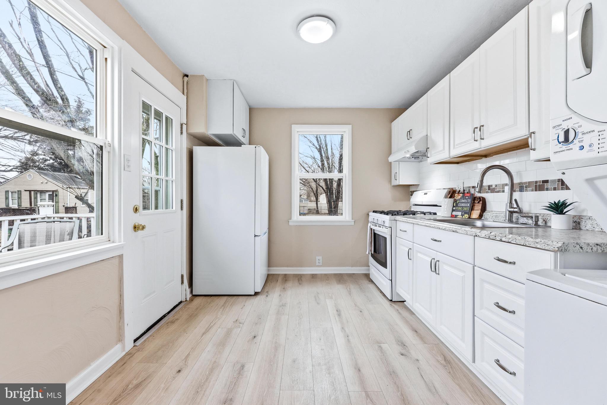 3 Victory Street Aberdeen, MD 21001 - Photo 3 of 26 a kitchen with stainless steel appliances a refrigerator a sink a stove and white cabinets with wooden floor