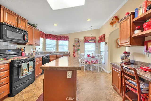 a kitchen with stainless steel appliances granite countertop a stove top oven a sink dishwasher and a fireplace with wooden floor