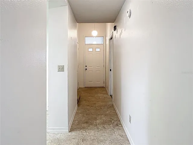 a view of a hallway with wooden floor and a bathroom