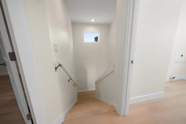 a view of an empty room with window and wooden floor