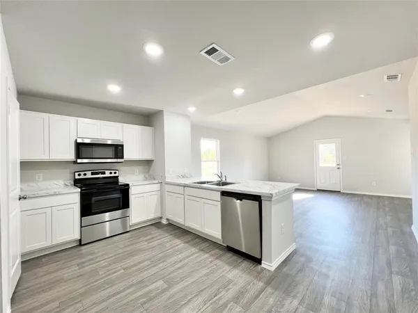 a kitchen with stainless steel appliances kitchen island granite countertop a stove top oven and sink