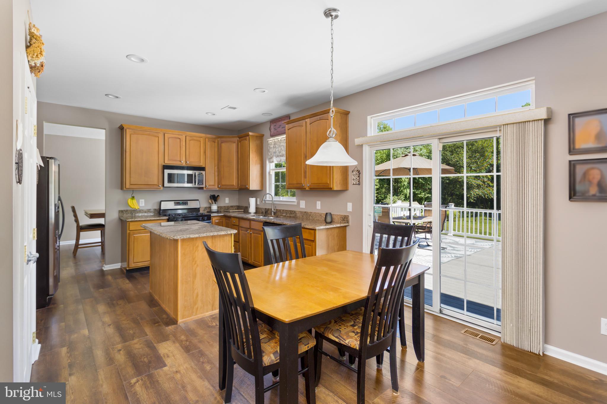 59 Birmingham Drive Columbus, NJ 08022 - Photo 14 of 45 a dining room with stainless steel appliances granite countertop a stove a refrigerator a oven a dining table and chairs with wooden floor