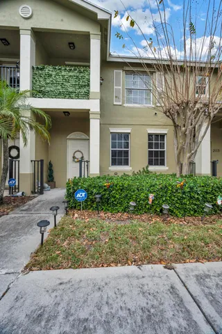 a front view of a house with a yard and potted plants