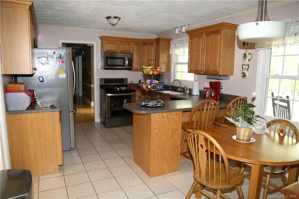 113 Sawtooth Lane, Unit 27 Stanley, NC 28164 - Photo 11 of 24 a kitchen with stainless steel appliances granite countertop a refrigerator a stove a sink a dining table and chairs with white cabinets
